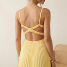Yellow dress with open back worn by a person, sitting on a beige chair.