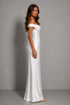 Woman wearing a white off-shoulder gown against a gray background