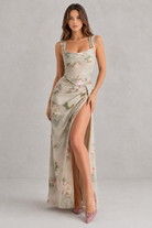 Woman wearing a floral dress with a high slit on a plain background