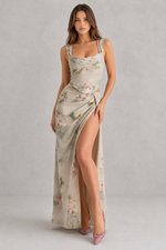 Woman wearing a floral dress with a high slit on a plain background