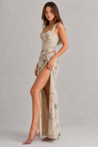Woman wearing a floral dress with a slit on a gray background