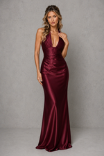 Woman wearing a burgundy satin evening gown against a gray background
