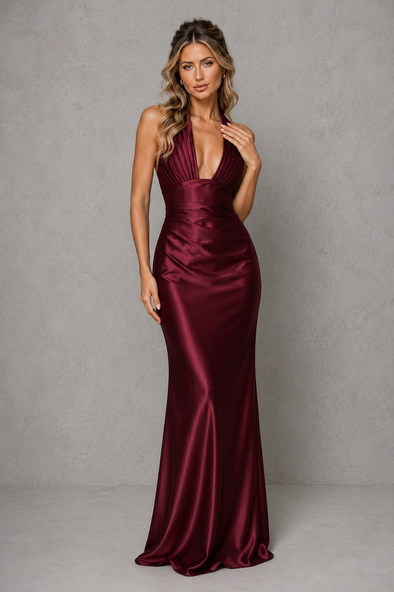 Woman wearing a burgundy satin evening gown against a gray background