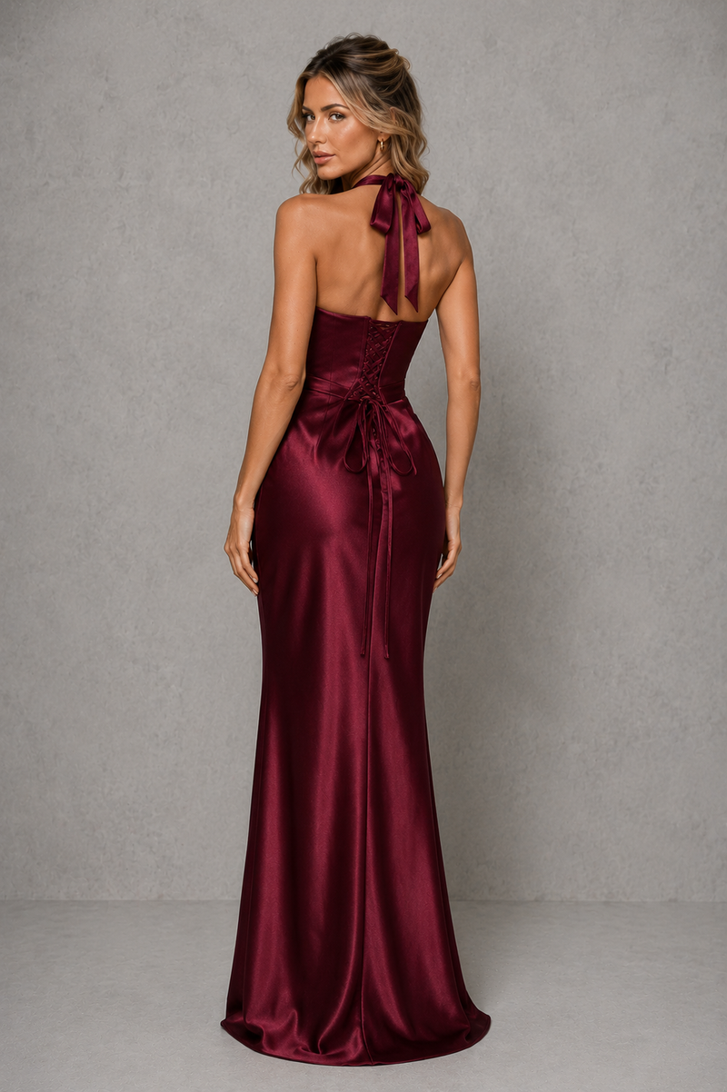 Woman wearing a burgundy satin gown with a gray background