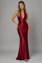 Woman wearing a red satin gown against a gray background