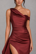 Burgundy one-shoulder dress with a slit on a gray background