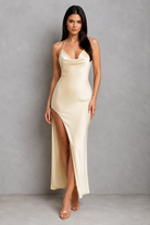 Woman wearing a beige slip dress with a high slit against a gray background