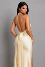 Woman wearing a beige open-back dress against a gray background
