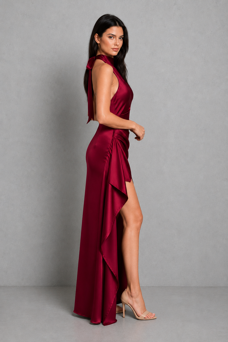Woman wearing a burgundy evening gown with a slit on a gray background