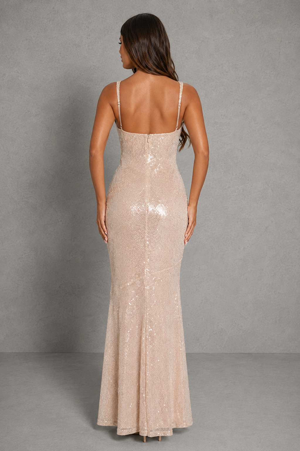 Woman wearing a beige sequin evening gown against a gray background