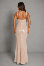 Woman wearing a beige sequin evening gown against a gray background