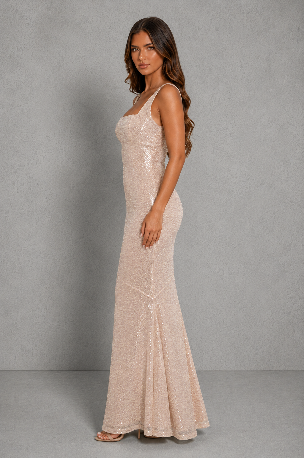 Woman wearing a beige sequin gown against a gray background