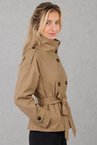 Women's short belted trench coat in a classic tailored design with an adjustable waist belt, lightweight fabric and a flattering fit, ideal for spring, autumn and everyday wear.