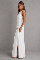 Woman wearing a white sleeveless dress with a slit on a gray background