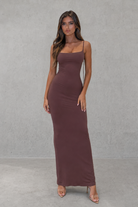 Woman wearing a brown dress against a gray background