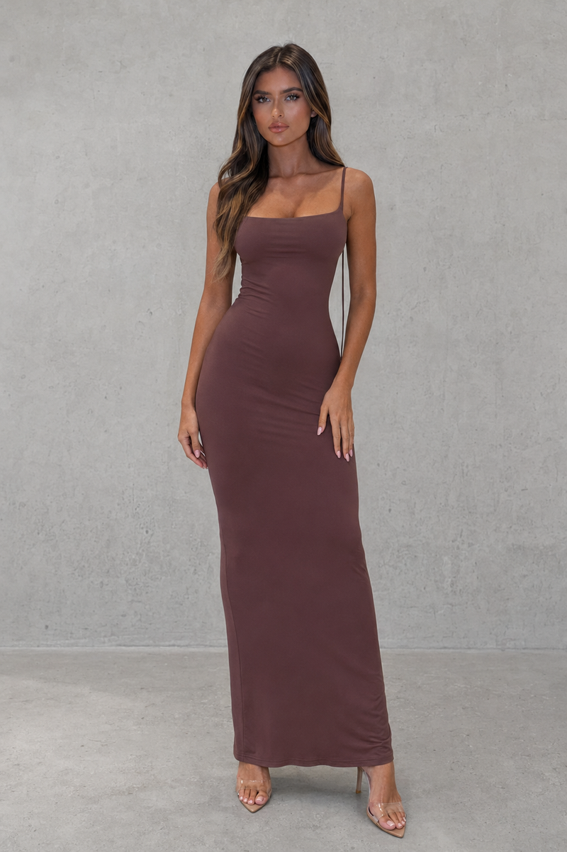 Woman wearing a brown dress against a gray background