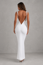 Woman wearing a white evening gown with thin straps against a gray background