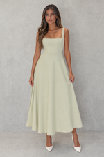 Woman wearing a light green dress against a gray background