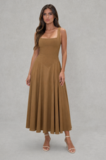 Woman wearing a brown dress against a gray background