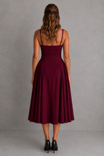 Woman wearing a burgundy dress against a gray background