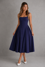 Woman wearing a navy blue dress against a gray background