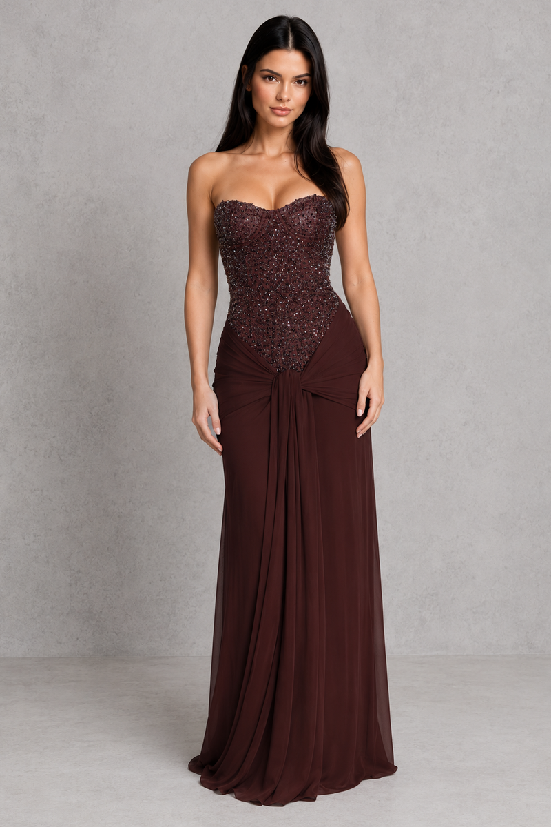 Woman wearing a strapless brown evening gown with a textured bodice on a gray background