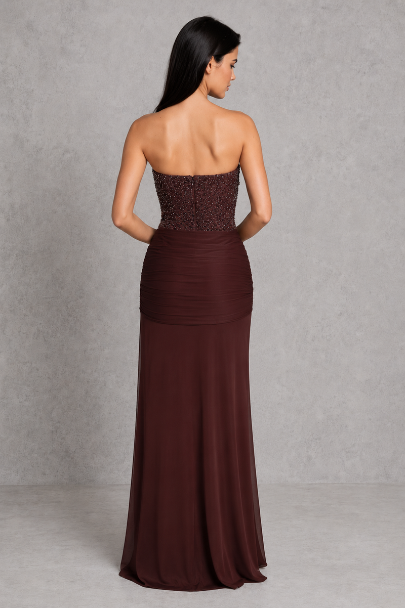 Woman wearing a strapless brown evening gown against a gray background