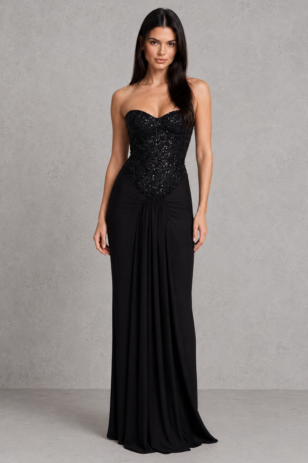 Woman wearing a black strapless gown with sequin detailing on a gray background