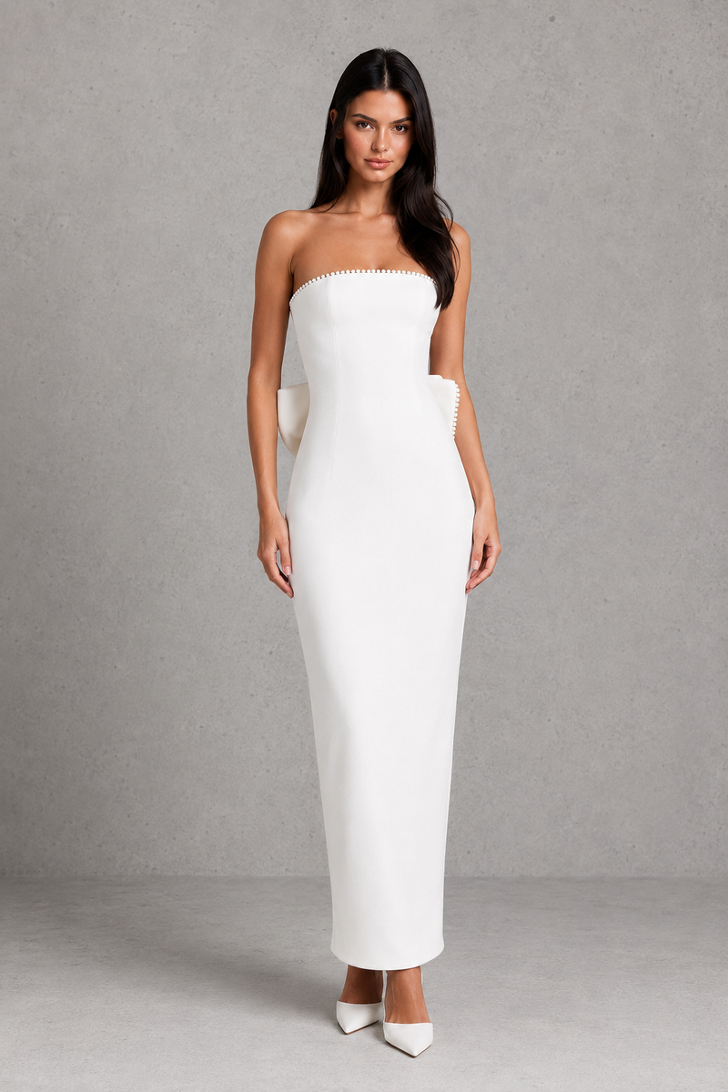 Woman wearing a strapless white gown against a gray background