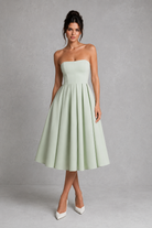 Woman wearing a light green strapless dress against a gray background
