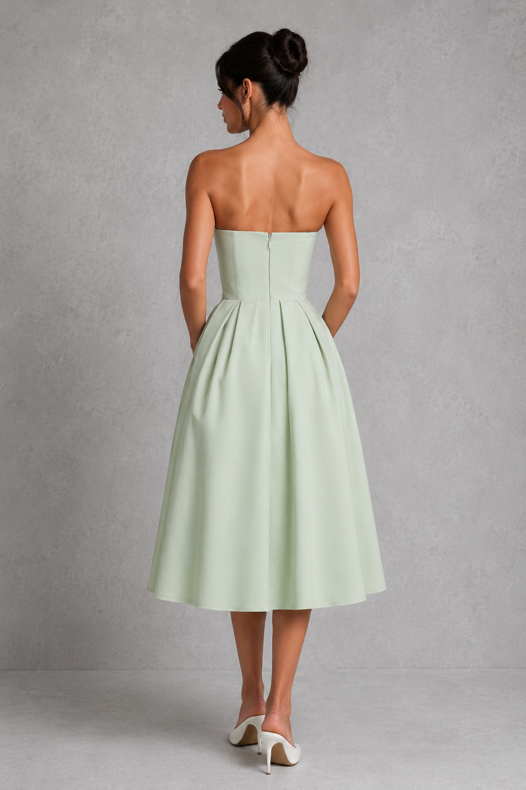 Woman wearing a light green strapless dress against a gray background