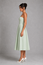 Woman wearing a light green strapless dress against a gray background