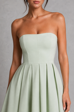 Light green strapless dress worn by a model against a gray background