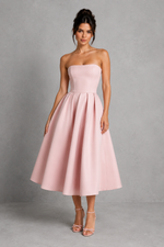 Woman wearing a strapless pink dress against a gray background