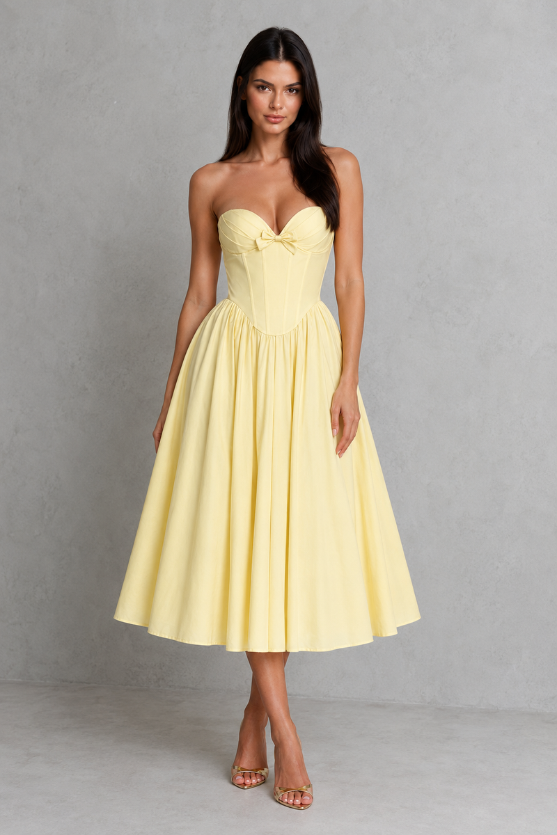 Woman wearing a yellow strapless dress against a gray background
