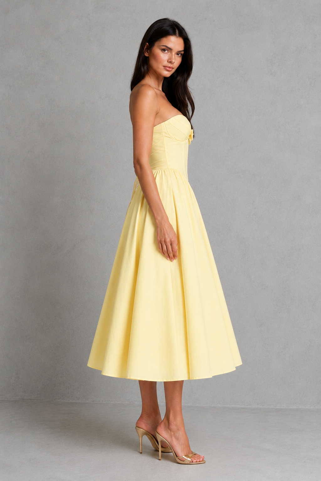 Woman wearing a yellow strapless dress against a gray background