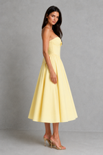 Woman wearing a yellow strapless dress against a gray background