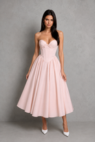 Woman wearing a pink strapless dress against a gray background