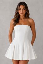 Woman wearing a white strapless dress against a gray background
