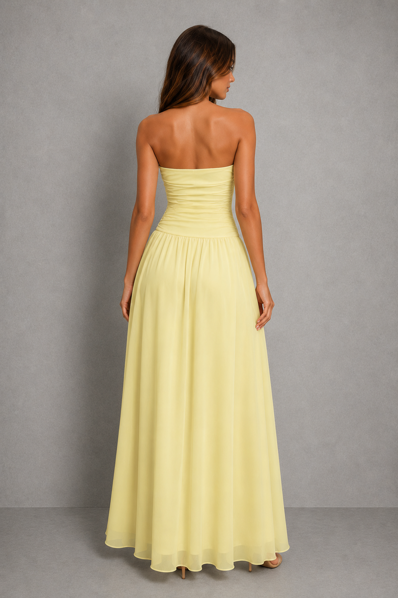 A woman shown from the back wearing a strapless, floor-length yellow dress against a plain gray studio background.
