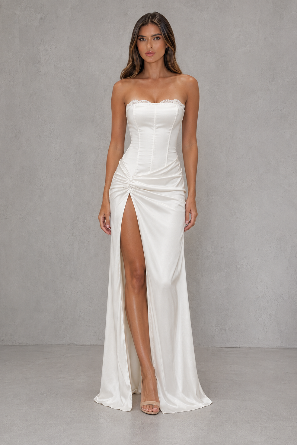 Woman wearing a strapless white gown with a high slit on a gray background