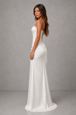 Woman wearing a white strapless gown with lace details on a gray background