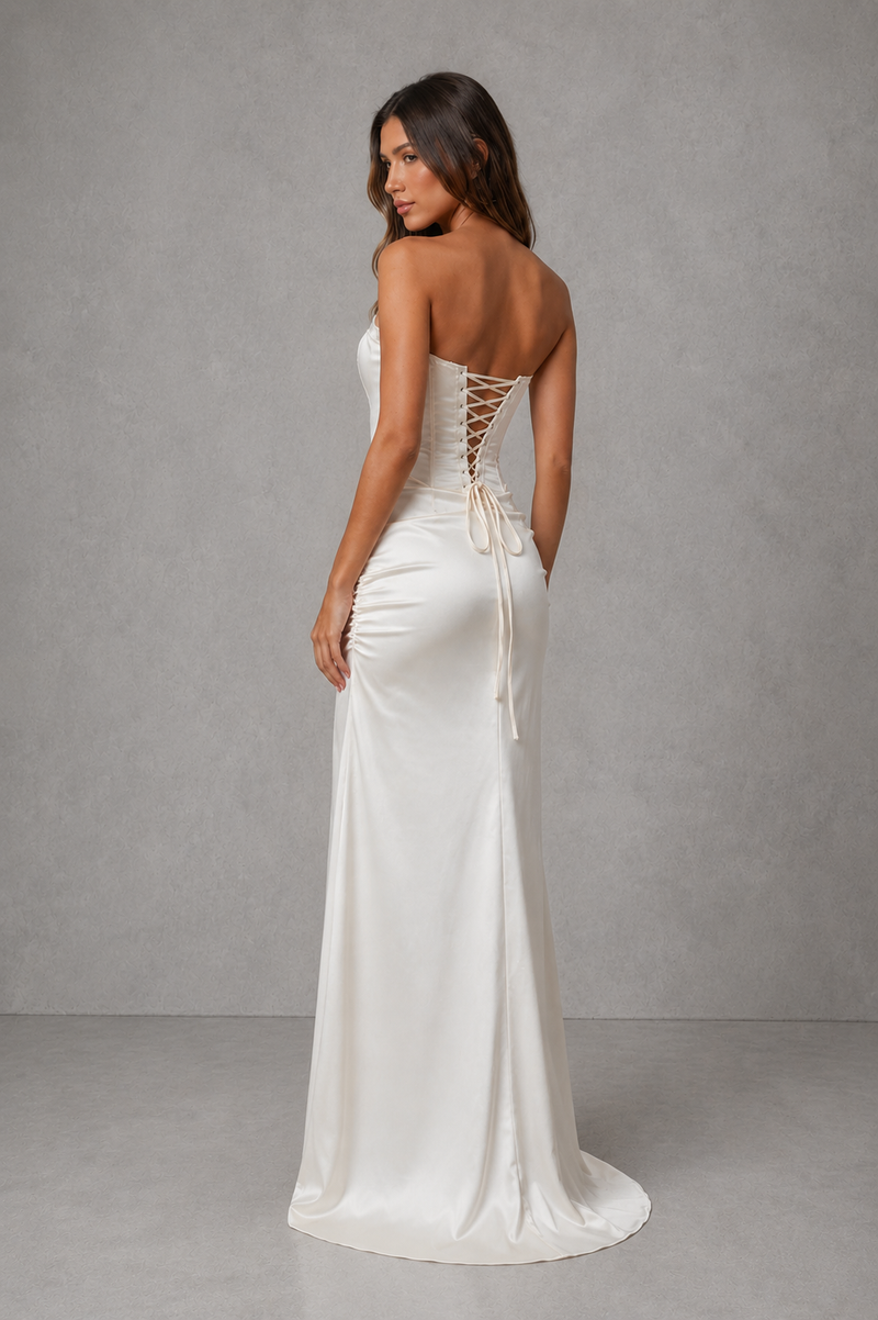 Woman wearing a white strapless gown with lace-up back against a gray background