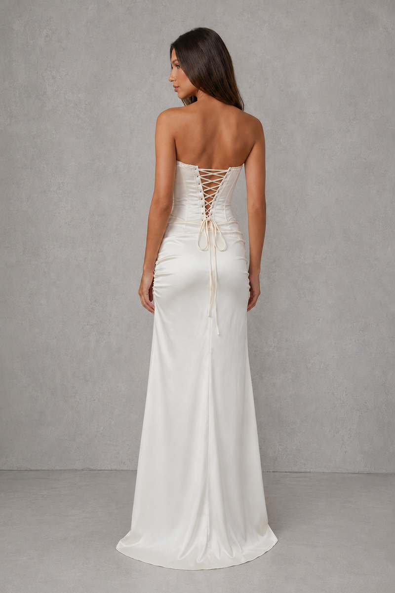 Woman wearing a white strapless gown with lace-up back against a gray background