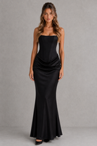 Woman wearing a black strapless gown against a gray background