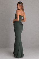 Woman wearing a strapless green evening gown against a gray background