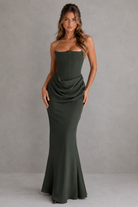 Woman wearing a strapless green gown against a gray background