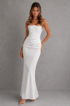 Woman wearing a white strapless gown against a gray background
