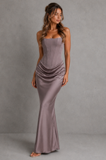 Woman wearing a strapless, floor-length dress against a gray background