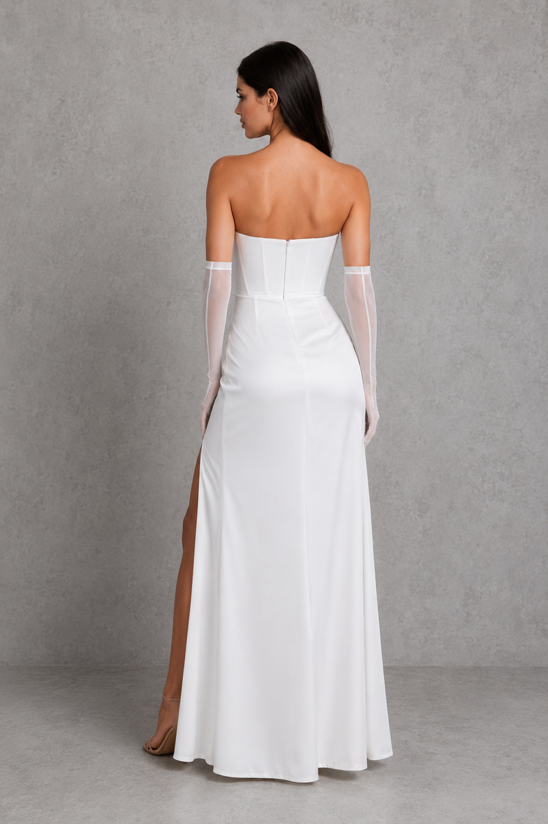 Woman wearing a white strapless gown with sheer sleeves against a gray background